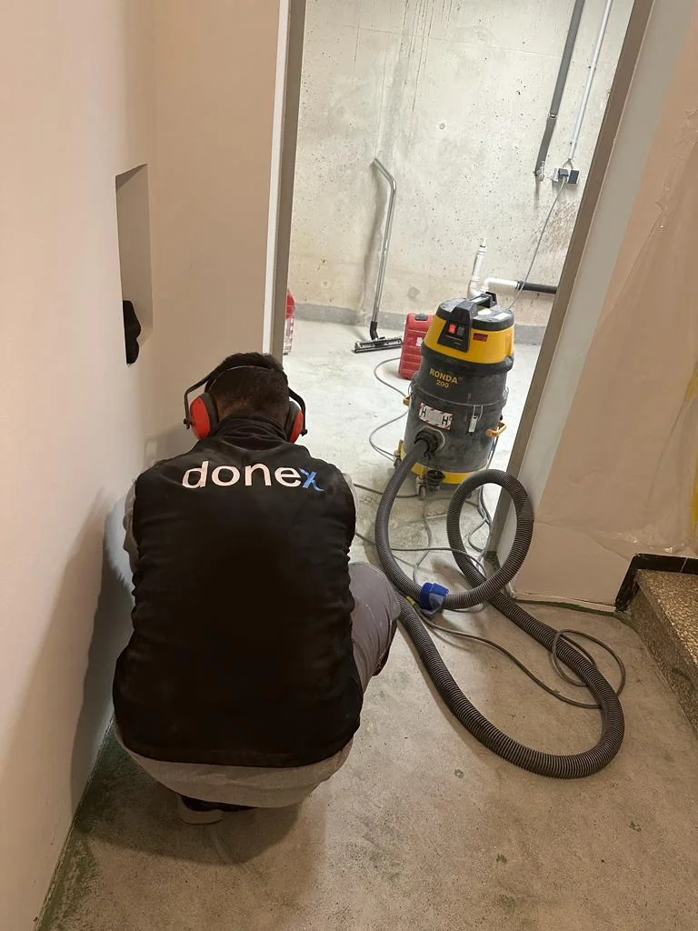 Handwerker mit Donex auf seiner Arbeitskleidung bei der Arbeit im Innenraum